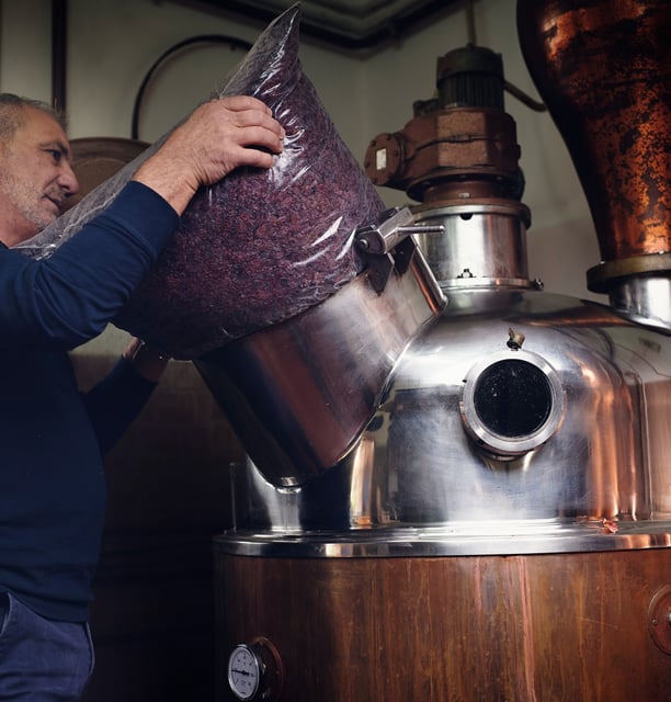Carico delle vinacce nell'alambicco in rame