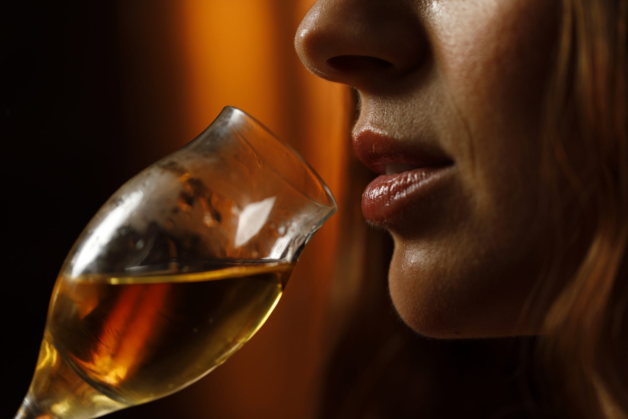 Primo piano di un calice di distillato portato alle labbra durante la degustazione