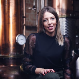 Una giovane donna della distilleria seduta davanti agli alambicchi in rame